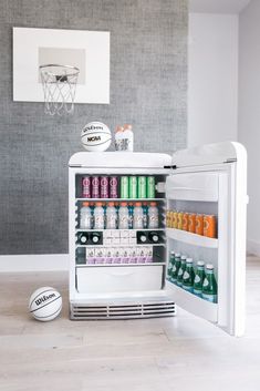 an open refrigerator with drinks and basketballs on the floor