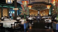 a dining room with tables and chairs covered in white tablecloths, decorated with floral centerpieces