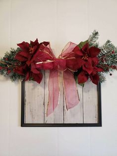 a christmas wreath with poinsettis and greenery hangs on the wall in front of a frame