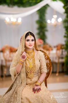 a woman sitting on top of a chair wearing a wedding dress and holding a necklace