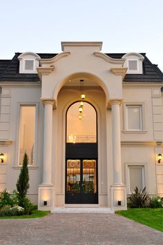 the front entrance to a large house with an arched doorway and two lamps hanging from it's ceiling