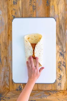 a tortilla being held up on a cutting board