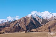 the mountains are covered in snow and brown grass, with a road running between them