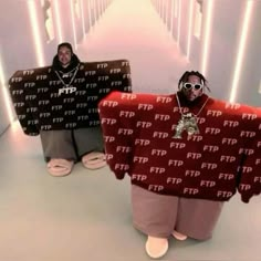 two men in matching sweaters standing next to each other on a long white hallway