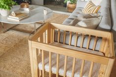 a baby crib in a living room next to a couch and table with books on it