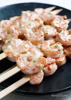 shrimp skewers are being served on a black plate