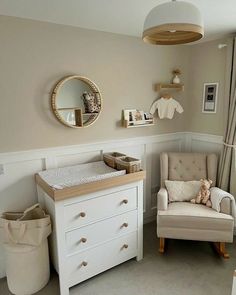 a baby's room with a chair, dresser and mirror