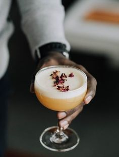 a person holding a wine glass filled with liquid and garnished with dried flowers