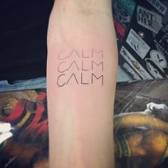 a person with a tattoo on their arm that says, calm calm and has the word written in black ink