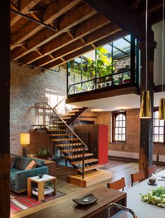 a living room filled with furniture and a spiral stair case next to a brick wall