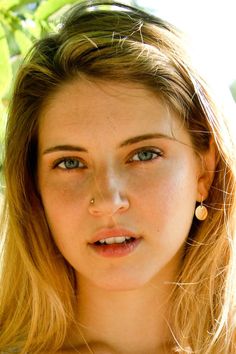 a young woman with blue eyes and piercings on her nose looking at the camera