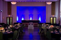 an empty banquet hall with tables and chairs set up for a formal function in front of a blue screen