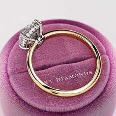 a diamond ring sitting on top of a pink velvet cushion with the words v t diamonds written below it