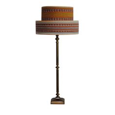 a lamp that is sitting on top of a wooden stand with a striped shade over it