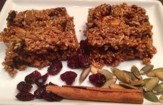 some granola bars on a white plate with dried cranberries and pumpkin seeds