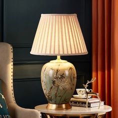 a table with a lamp on top of it next to a chair and a book