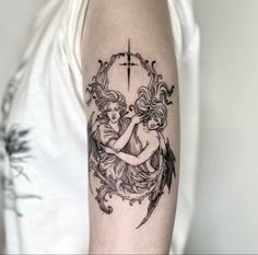 a woman with an angel tattoo on her arm is holding a cross and surrounded by wings