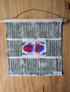 a piece of cloth hanging on a wooden wall with two red and blue flowers in the center