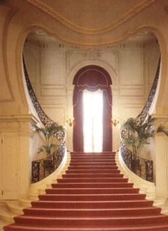 a staircase with red carpet leading up to an open door in the middle of it