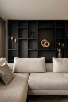 a white couch sitting in front of a book shelf filled with books and vases