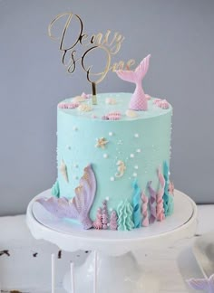 there is a blue cake with mermaid decorations on it