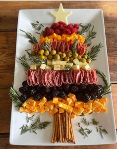 a christmas tree made out of different types of food on a white plate with pine branches