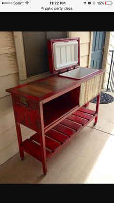 an old red table with a cooler on it's top and some drawers underneath