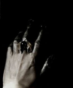 a person's hand with black and white nail polish holding a bat in the dark