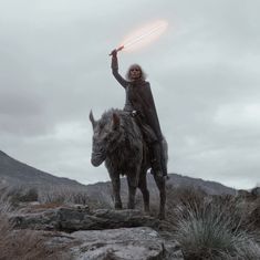 a woman riding on the back of a horned animal with a light saber in her hand