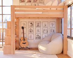 a bedroom with a loft bed, white chair and guitar on the floor in front of it