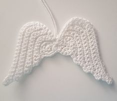 crocheted white angel wings hanging on a wall next to a photo of the back of an ornament