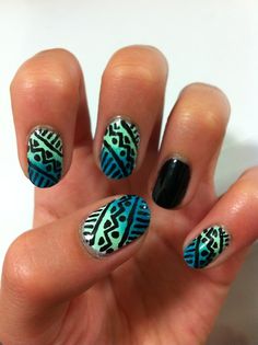 a woman's hand with some blue and black nail polishes on her nails