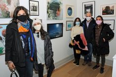 group of people wearing face masks standing in front of paintings