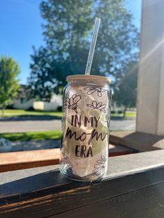 a mason jar with writing on it and a straw sticking out of the lid that says, in my mom era