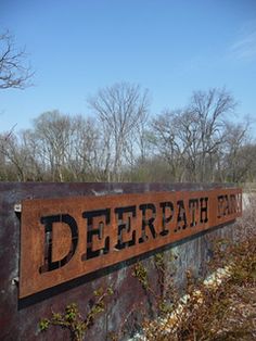 a sign that says deerpath farm on it in front of some bushes and trees