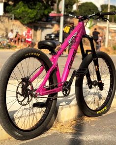 a pink bike is parked on the side of the road in front of a curb