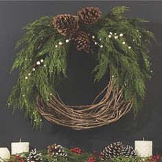 a christmas wreath with pine cones and candles