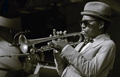 a man in a suit and hat playing a trumpet