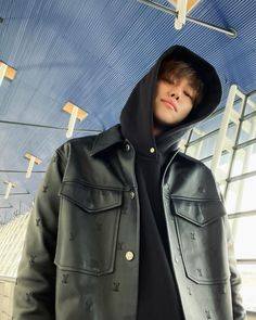 a young man wearing a leather jacket and hoodie