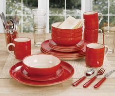 a table set with red dishes and silverware