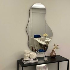 a mirror sitting on top of a black table next to a vase with flowers in it