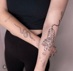 a woman with a tiger tattoo on her arm holding onto a snake and snake bracelet