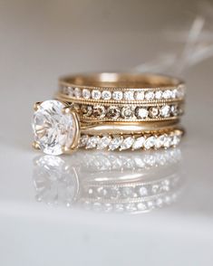 two gold wedding rings with white diamonds on the top and one has a large diamond in the middle