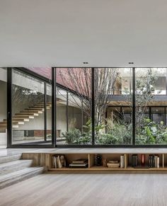 an open living room with large windows and bookshelves in front of the stairs