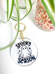 a keychain that says spooky season with a ghost in the center