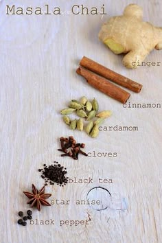 the ingredients for masala chai on a white tablecloth with cinnamon, cardamom, cloves, star anise, black pepper and ginger