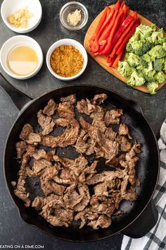 steak and broccoli cooking in a skillet with spices, seasonings, and other ingredients