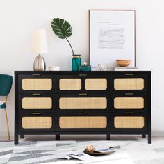 a black dresser with wicker inserts and gold trim on the drawers, next to a green chair