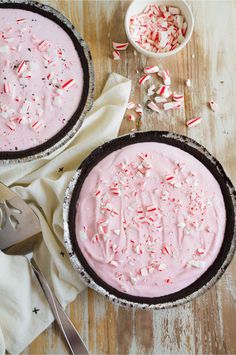 two pies with pink frosting and sprinkles are on the table