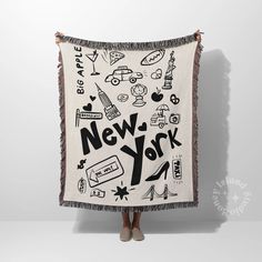 a woman is holding up a new york blanket